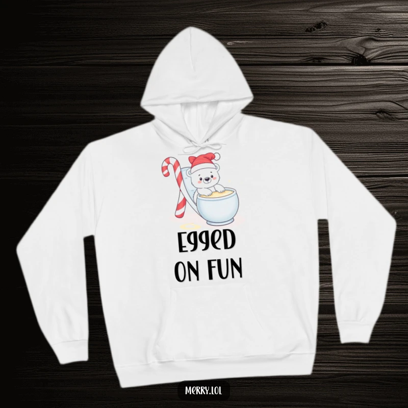 Funny hoodie illustration of a baby polar bear playfully sliding down a candy cane slide into a bowl of eggnog.